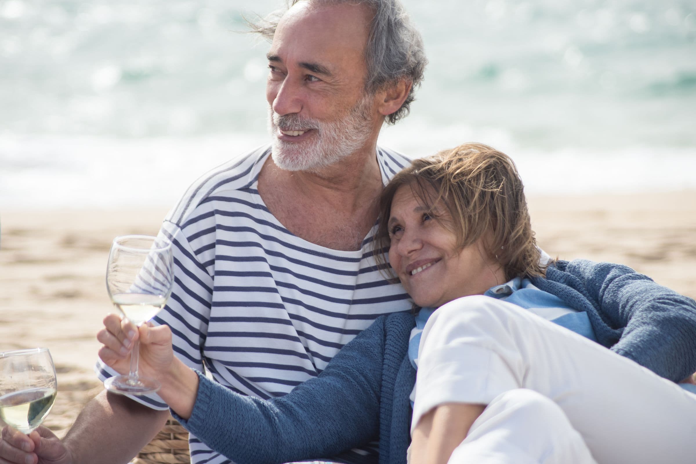 An older couple sharing a glass of wine by the sea